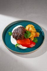 Juicy grilled beef steak with golden roasted potatoes, red sweet pepper, creamy white sauce and...