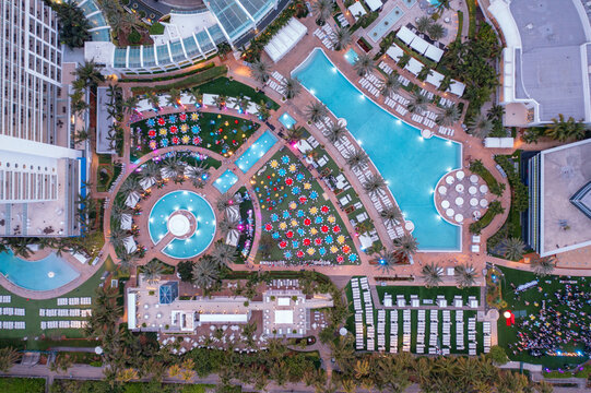 Aerial view of vibrant colors and textures meet tranquil turquoise pools and manicured lawns, framed by towering buildings, Miami, Florida, United States.
