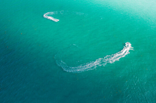 Aerial view of jet skis carving white wakes into the turquoise sea, creating dynamic patterns on the water's surface, Miami Beach, Florida, USA.