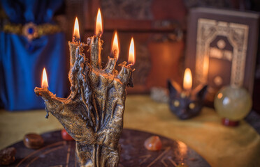 Enchanted ritual altar with burning candle, mystical hand, and ancient grimoire on golden cloth