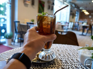 Person is holding a glass of tea with a straw in it