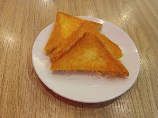 Grilled cheese toasted bread. The sandwich is cut into triangles and served on a white plate.