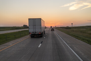 Truck driving on highway at sunset