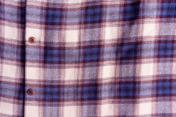 Close-up view of a plaid checkered shirt made of cotton fabric material of blue purple colour decorated with brown buttons with copy space used for cold autumn season as cozy casual comfortable cloth