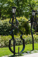 Park with original sculptures on lampposts in form of human figures with musical instruments. Metal...