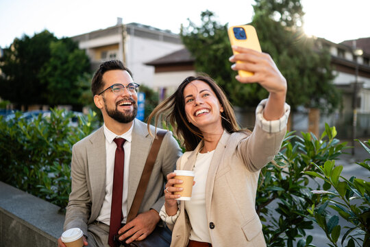 Business people taking selfie while drinking coffee outdoors