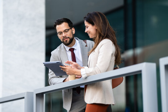 Business colleagues using tablet and discussing work outdoors