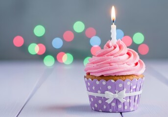 A single pink frosted cupcake with a lit candle and colorful bokeh lights in the background, perfect for a birthday celebration