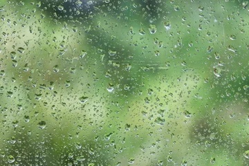 Gordijnen Olijf rain water drops on the window glass with green background blurry.  © Uuganbayar