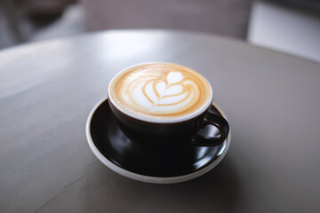 Closeup image of a cup of hot latte coffee with latte art on the table in cafe