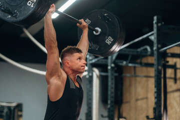 Training process, session. Athletic man performing weightlifting exercises with a barbell in a gym