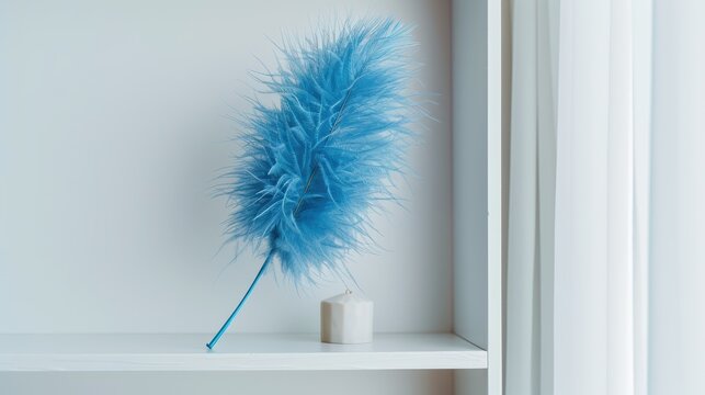 A vibrant blue feather duster rests elegantly on a white shelf, adding a pop of color to the minimalist decor around it.