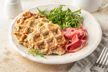Zucchini waffles served with arugula salad and prosciutto close up. Healthy vegeterian food