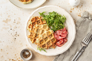 Zucchini waffles served with arugula salad and prosciutto. Healthy vegeterian food top view