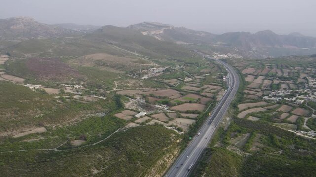 M2 motorway cutting through green hills and patchwork fields near Kallar Kahar, Punjab, Pakistan