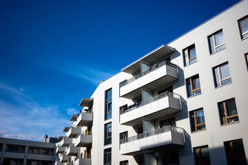 The facades of white apartment buildings against a blue sky. Modern multi-family housing.