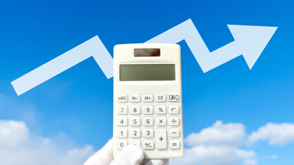 白手袋をはめた手で持つ計算機とジグザグに上昇する矢印