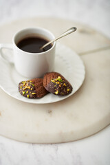 Cup of coffee with chocolate madeleines on marble table.