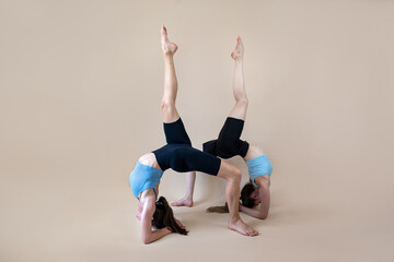 Obraz premium Two young fitness women in sportwear stretching practice isolated at studio