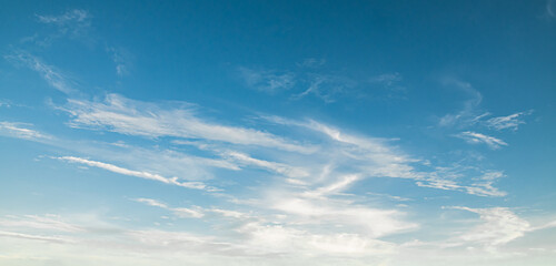 the sky is clear blue with fluffy white clouds, the sky is very bright, and the sun shines.