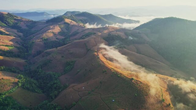Aerial view of sunlight shines over barren deforest mountain with foggy among agricultural area in countryside at Chiang Mai, Thailand