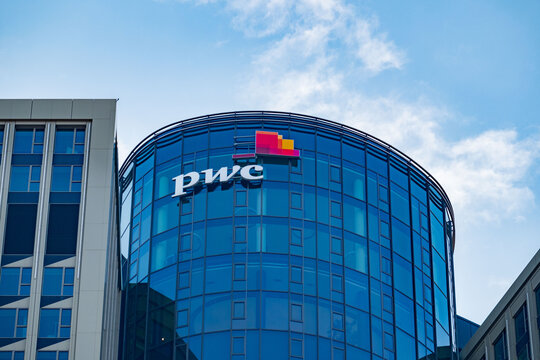 PwC logo on glass facade, high-rise glass office building against blue sky, finance and consulting, global economy, professional financial services in Germany, Frankfurt - February 9, 2025