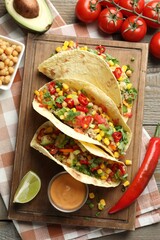 Tasty vegetarian tacos with chickpeas, corn and quinoa served on wooden table, flat lay