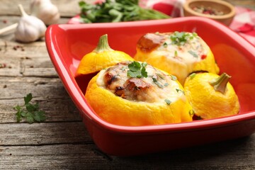 Tasty stuffed pattypan squashes in baking dish on wooden table, closeup