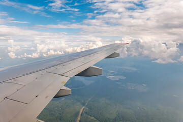 View from the airplane window at a beautiful cloudy sky and the airplane wing