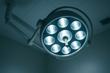 Bright surgical lamp head against clean ceiling, cinematic perspective, no people