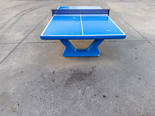 Bright blue table tennis table situated at a seaside promenade during a pleasant evening with...
