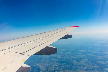 View from the airplane window at a beautiful blue clear sky and the airplane wing