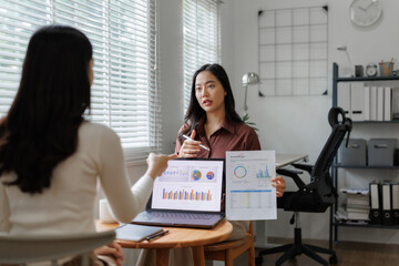 Businesswomen discussing financial charts and data analysis in office meeting