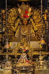Close-up view of a Tibetan Buddhist man deity in gold ornamental altar statue, symbolizing protection and the destruction of evil spirits.