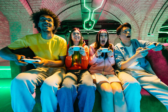 Multiethnic group of young friends playing videogames at home