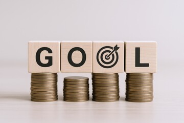 Financial Goal Achievement: Wooden Blocks Spelling 'GOAL' on Coin Stacks, Representing Investment and Success