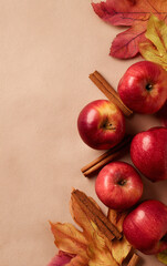Apples with cinnamon sticks and autumn leaves on beige. Fall harvest concept for thanksgiving day card, autumn season greetings, and cooking recipe background