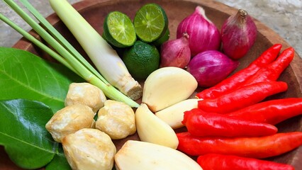 Spices or Rempah-rempah, lemongrass, chilies, garlic, shallots, lime, candlenuts, bay leaves and lime leaves as spices for Indonesian cooking. Indonesian spices on a wooden plate