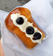 Rum baba with whipped cream and cherries resting on white napkin