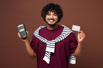 Young Indian man in purple t-shirt sweatshirt tied over shoulders casual clothes hold modern bank...