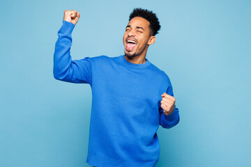 Young man of African American ethnicity wear sweatshirt casual clothes doing winner gesture...