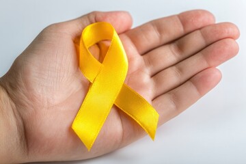 Yellow ribbon sits in the open palm of a human hand
