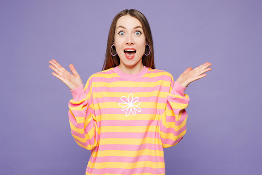 Young shocked surprised excited overjoyed woman she wears yellow sweatshirt casual clothes spread hands look camera isolated on plain pastel light purple background studio portrait. Lifestyle concept.