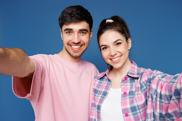 Fototapeta premium Close up young couple two friends family man woman they wearing pink casual clothes together doing selfie shot pov on mobile cell phone hug isolated on plain blue background studio. Lifestyle concept.