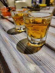 Close-up of whiskey shots in small glasses on a rustic wooden table in a bar setting