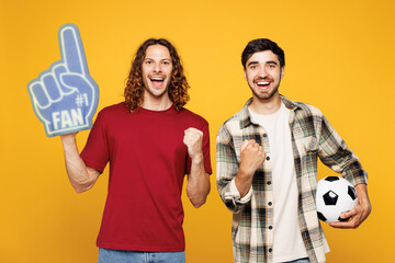 Young two friends men sport fans wearing casual clothes foam 1 fan glove finger up cheer up support...