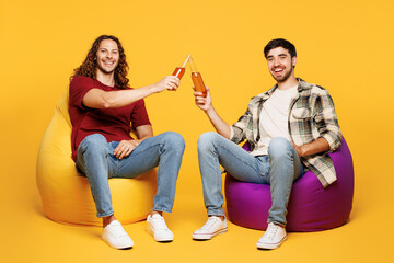Full body young happy two friends buddies men they wear casual clothes together sit in bag chair...