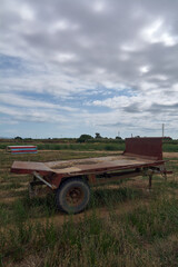 Fototapeta premium Neglected farm trailer under a cloudy sky.
