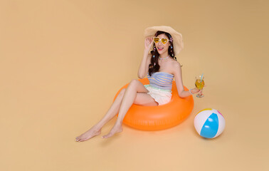 Summer vacation travel woman relaxing on orange inflatable ring holding cocktail beside beach ball...
