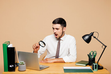 Young shocked sad successful employee business man wear white shirt tie sit work at office desk...